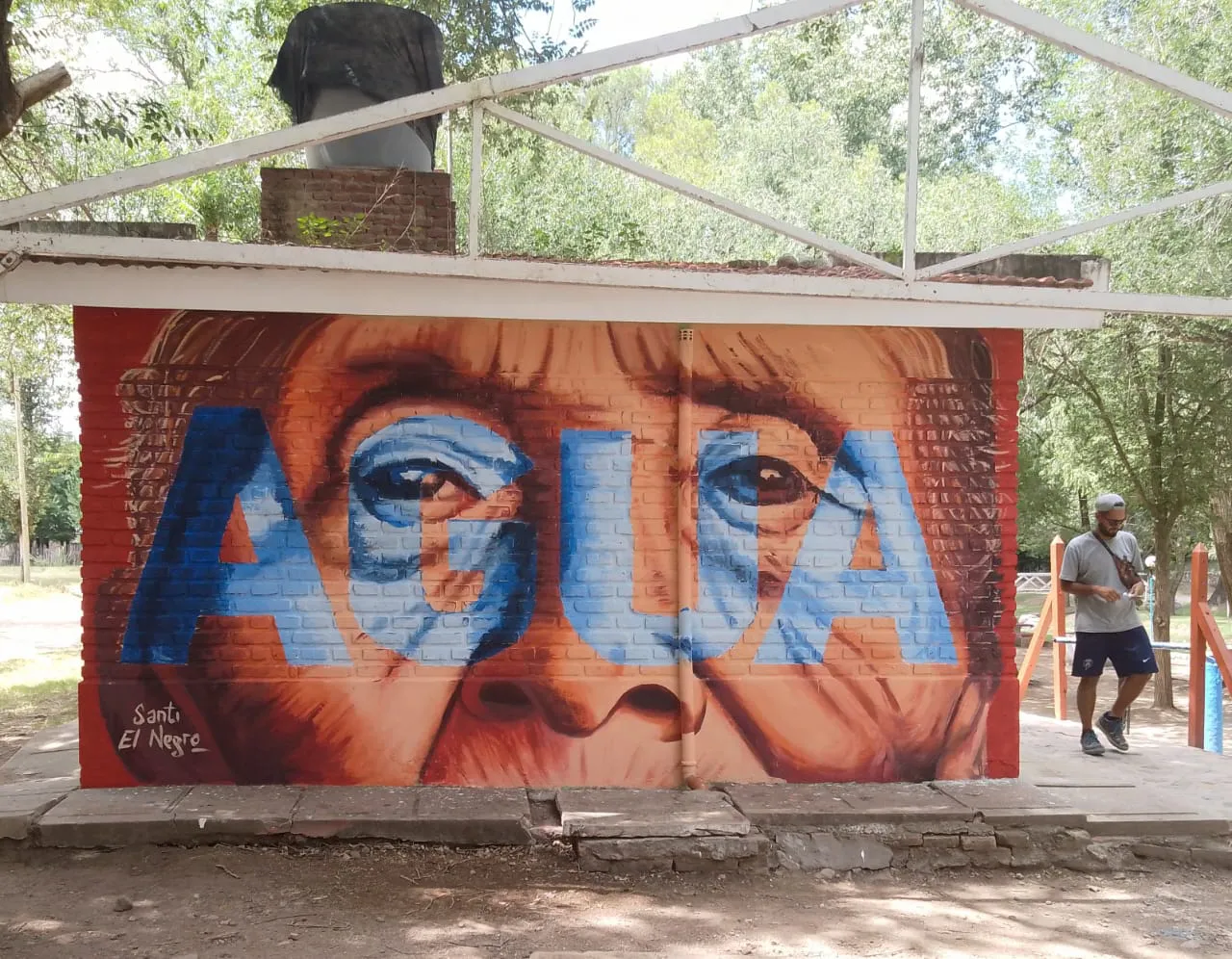 mural del rostro de una mujer de un pueblo originario, se visualiza integrada al muro la palabra agua
